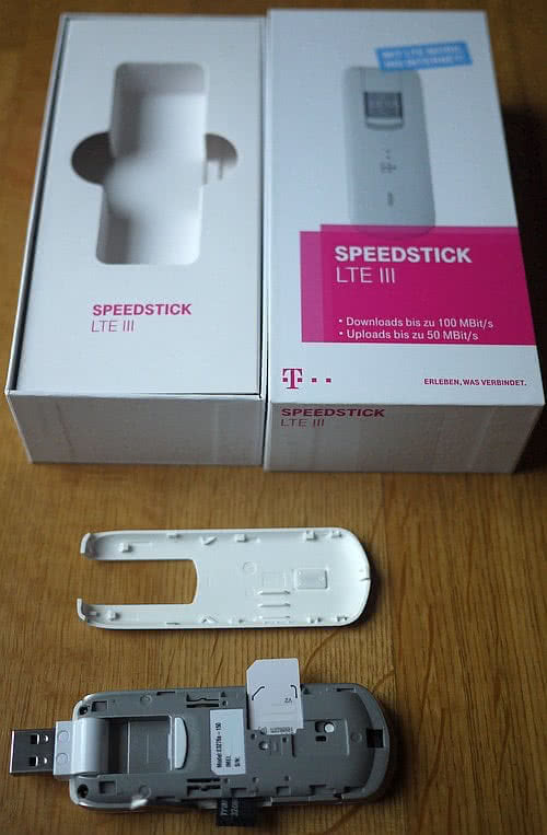 Foto: Telekom Speedstick III mit abgenommenem Deckel, sichtbaren Schnittstellen und Originalkarton im Hintergrund